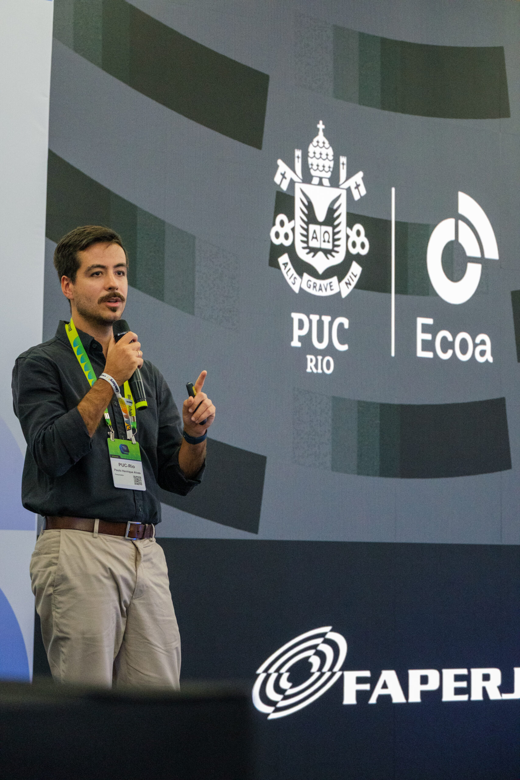 Apresentação sobre blockchain, com painel do Instituto Ecoa PUC-Rio e FAPERJ ao fundo